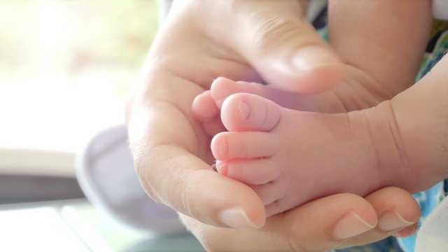 Close-up of parents hands holding feet newborn and baby sleep on her arms. Concept of happy family desire in no noisy home and carefree