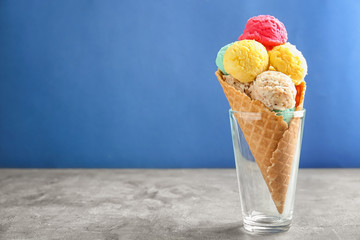 Colorful ice-cream scoops in waffle cone on blue background
