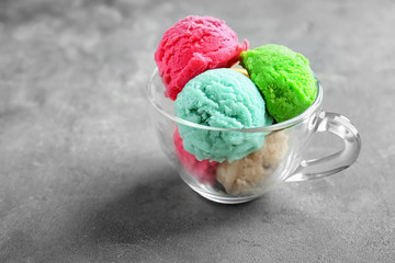 Scoops of ice-cream in glass cup on grey background