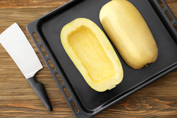 Halves of fresh spaghetti squash on baking sheet