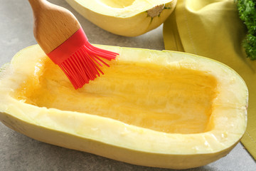 Applying olive oil on half of spaghetti squash