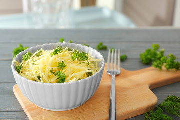 Bowl with flesh of spaghetti squash on wooden board