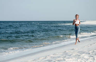  Athletic fitness woman running on the beach. Outdoor workout.