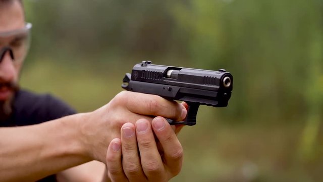 Young man is shooting from a gun, close up. Slow motion