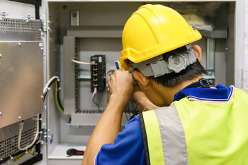 Electrician with a screwdriver macro connect wires on the background of electrical cabinet with...