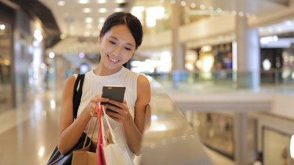 Woman use of mobile phone and holding shopping bags in shopping center