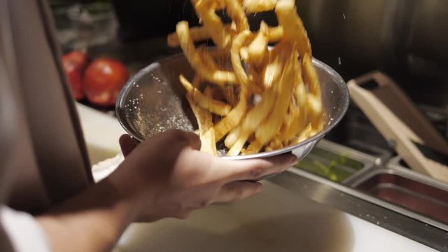 High Quality Slow Motion Footage Of Parsnip Fries Being Tossed In Salt In A Fancy Restaurant Kitchen.