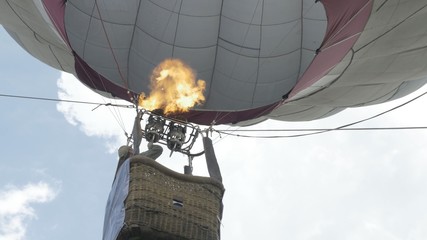 Obraz premium Close up of a hot air balloon flying in the sky. Flying-up balloon with a basket against the blue sky the bottom view