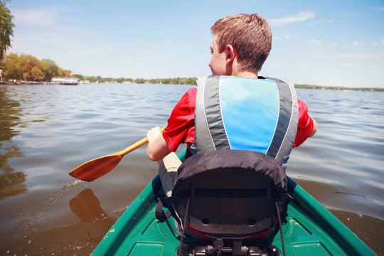 Boy paddling a canoe on a lake