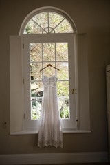 Wedding dress hanging on window in room