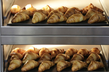 Freshly homemade croissants in bread oven cooking for breakfast.