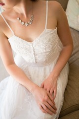 Midsection of beautiful bride wearing necklace sitting on sofa