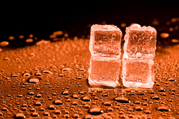 Water drop with ice cubes on lighting red background.