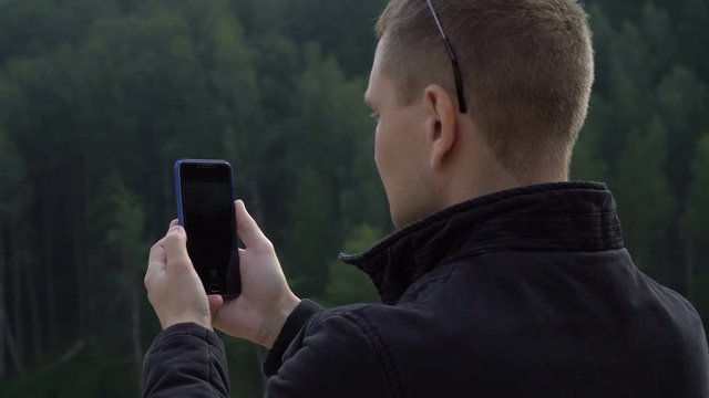 Young tourist man with smart cell phone taking picture selfie of amazing nature