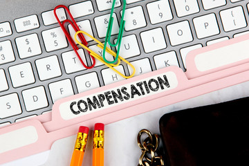 Compensation concept. Folder Register on Background of Computer Keyboard.
