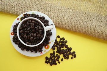 Coffee bean in a cup on a yellow background.