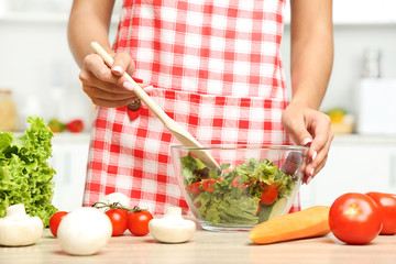Young woman cooking salad in the kitchen