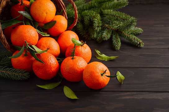 Fresh tangerine clementines with leaves on dark wooden background, selective focus