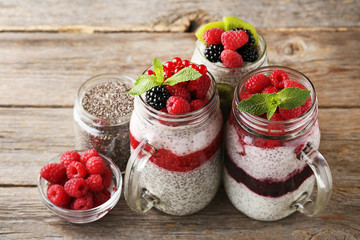 Chia pudding with berries in glass jars on wooden table