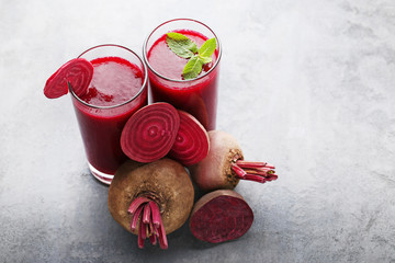 Fresh beets juice in glass on grey wooden table