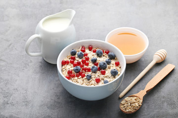 Oat flakes in bowl with berries on grey wooden table