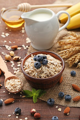 Oat flakes in bowl with blueberries on wooden table