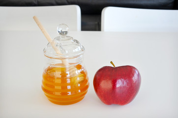 Honey jar and red apple on a white table