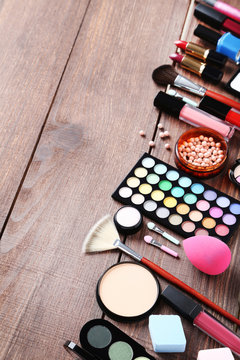 Different makeup cosmetics on brown wooden table