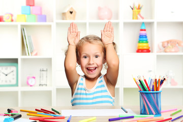 Little girl sitting and drawing at the table