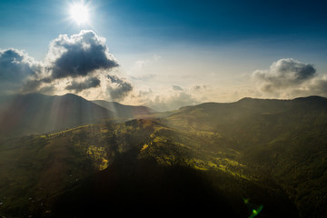 Beautiful panoramic view from the air to the Carpathian Mountains with clouds and sun rays in the foreground
