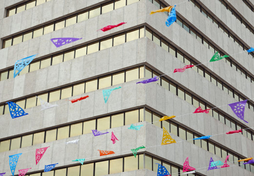Bunte Wimpel vor einer Bürohausfassade in Mexiko