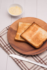 Close-up of slice of toast bread with butter on wood table