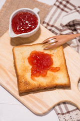 Toast with strawberry jam on a plate on table.