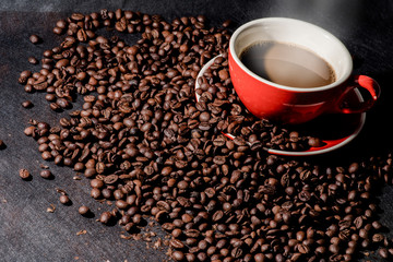 Hot coffee in red cup and coffee beans are the background.