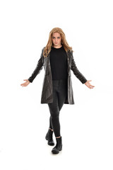 full length portrait of girl wearing black clothes and long leather jacket. standing pose in white background.