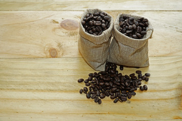 Coffee beans inside the sack bag on a wooden background.