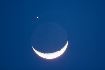 Naklejka premium Crescent Moon on a night sky with Jupiter and satellites. 