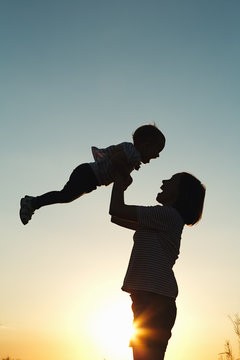 Silhouette of a happy woman with her child at sunset.