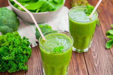 Fresh green smoothies in glass with ingredients on the dark rustic wooden table. Healthy, diet, detox lifestyle concept. Selective focus. Copy space.