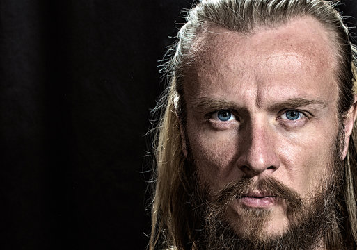 Brutal handsome man face. Close-up blonde nordic brutal man face on black background. 