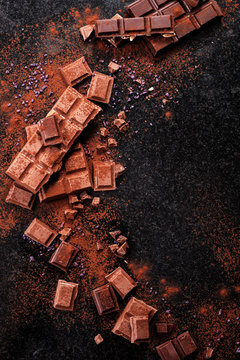 Broken Chocolate Pieces And Cocoa Powder On Marble.