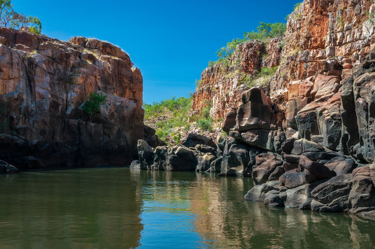 Rocky cliff face with reflections on the Katherine River banks, the end point of the cruise tour in the dry season at Katherine Gorge in Nitmiluk National Park, Northern Territory, Australia.