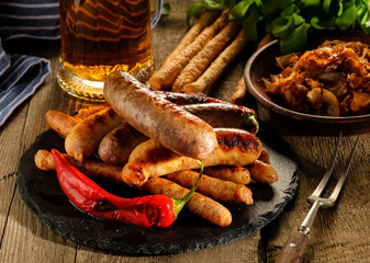 Grilled sausages and stewed cabbage with a mug of beer on a wooden table