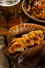 Grilled sausages and stewed cabbage with a mug of beer on a wooden table