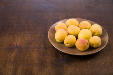 Apricots in a plate on a wooden table.