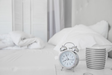 Alarm clock at 8 am. to wake up. White bedroom. Watch and mug. Good morning