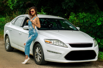 attractive women in jeans dress stands near the white car