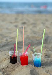 three glasses with icy drinks on the sand