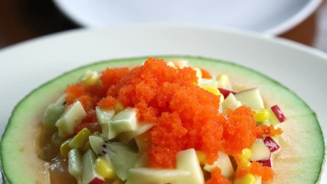fruit salad in cantaloupe bowl. Scooped water melon, melon, salad dressing and fish eggs on top healthy food