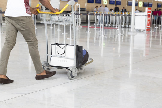 Airport luggage Trolley with suitcases, unidentified man woman walking in the airport, station, France